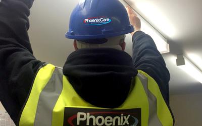Phoenix group worker fixing light fixture